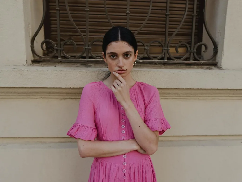 A woman in a pink dress against a cream wall, made with FLUX 3 Image Klein