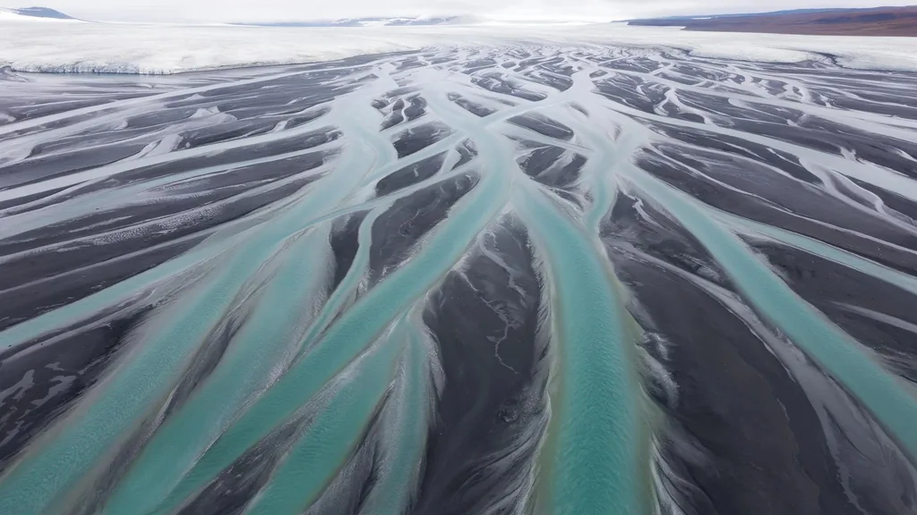 Aerial drone photograph of a braided glacial river delta in Iceland, turquoise channels weaving through black…, made with FLUX 3 Image Klein
