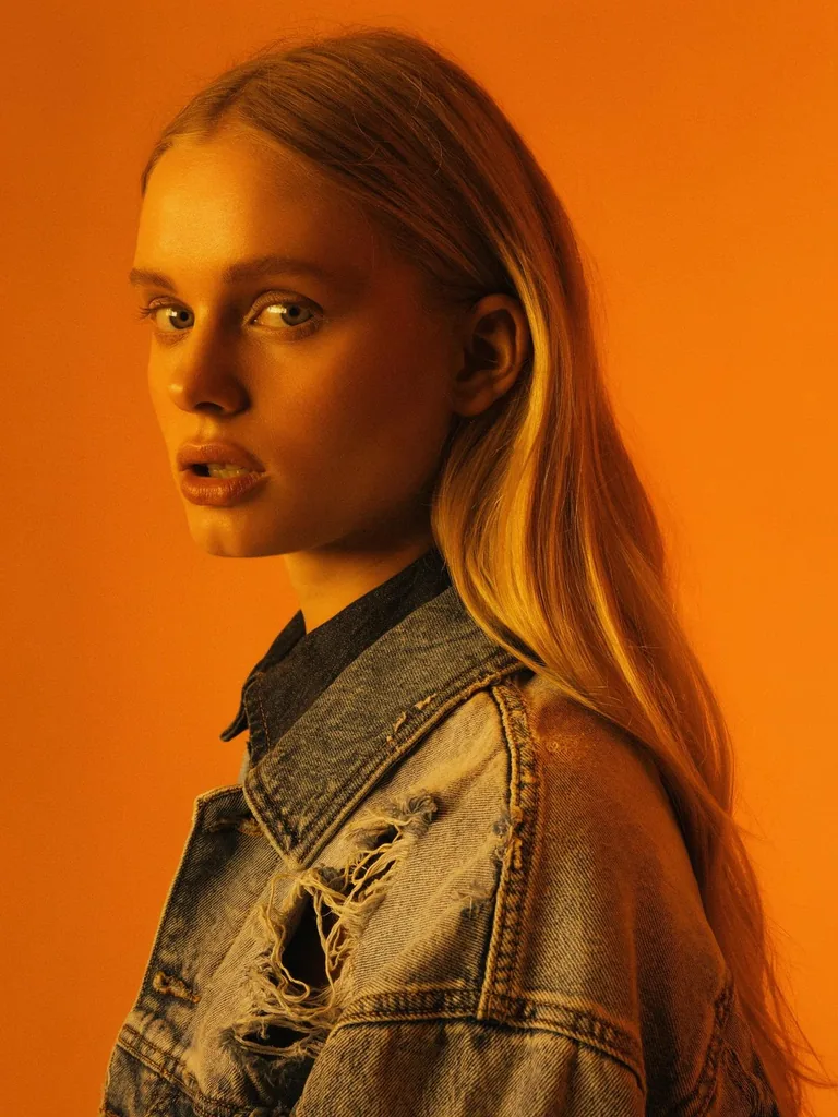 Portrait of a woman in a denim jacket against orange, made with FLUX 3 Image Klein