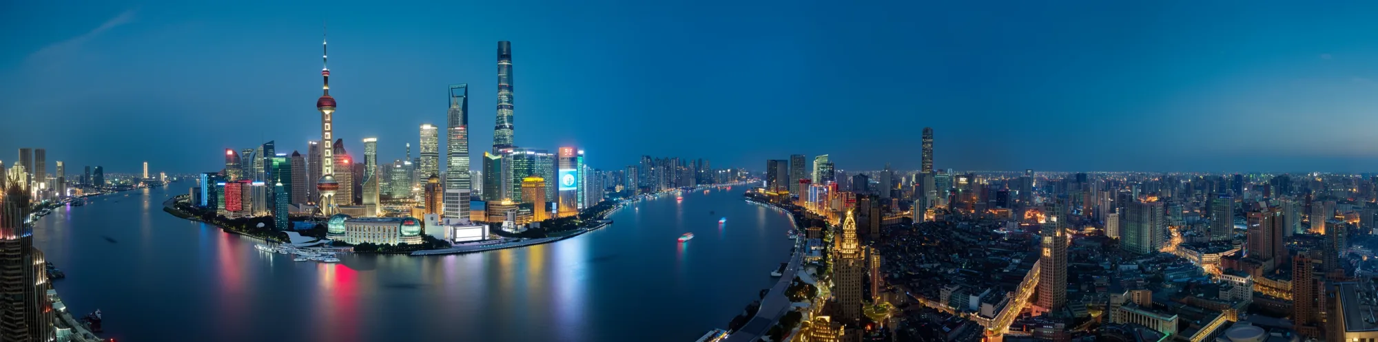 An ultra-wide 4:1 panorama of the Shanghai skyline and the Huangpu River at dusk
